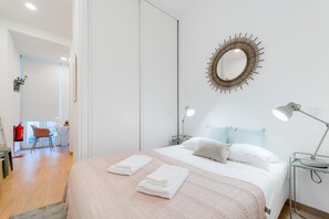A modern hotel room with a large bed, bedside lamps, a decorative mirror, and a desk with a chair. - Nomad s Boulevard Flats - Suite Terrace 1 (Porto)