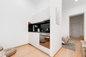 A compact kitchen with white cabinets, a black countertop, and a stainless steel range hood. - Nomad s Boulevard Flats - Suite Terrace 1 (Porto)