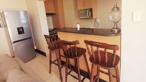 A compact kitchen with a refrigerator, microwave, stove, and bar stools. - Luxury Flatlet in the heart of Umhlanga (uMhlanga)