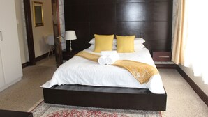 A hotel room with a large bed, a dark headboard, and a patterned carpet. - Luxury Flatlet in the heart of Umhlanga (uMhlanga)