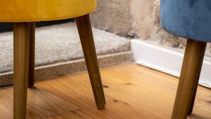 Two ottomans, one yellow and one blue, with wooden legs, placed on a wooden floor against a stone wall. - Nomad s Netto Subway - Lovely Terrace (Porto)