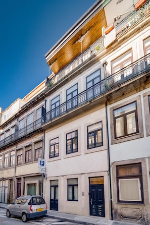 A multi-story building with balconies, a parking sign, and a car parked on the street. - Nomad s Netto Subway - Lovely Terrace (Porto)