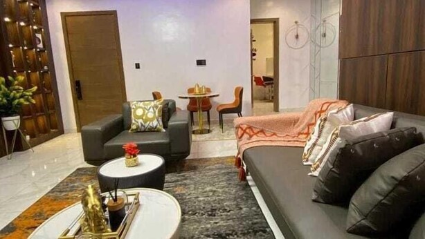 Un salon moderne comprenant un canapé, des fauteuils, une table basse et un coin repas avec une table et des chaises.
