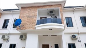 Un immeuble de deux étages doté d’un balcon, d’une antenne parabolique et de climatiseurs.