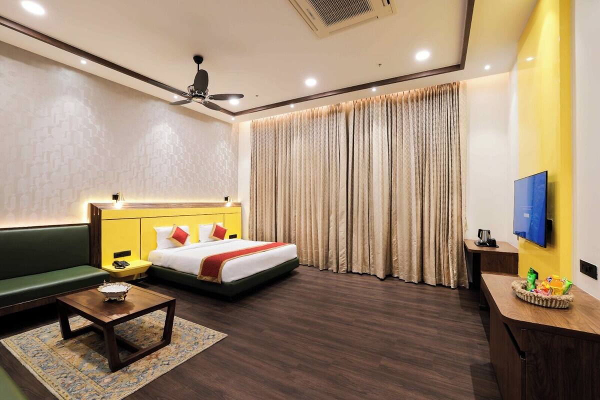Ein Hotelzimmer mit Bett, einer Couch, einem Fernseher und einem Schreibtisch.
