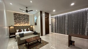Ein modernes Hotelzimmer mit einem Bett, einer Couch, einem Couchtisch, einem Deckenventilator und einem großen Fenster mit Vorhängen.