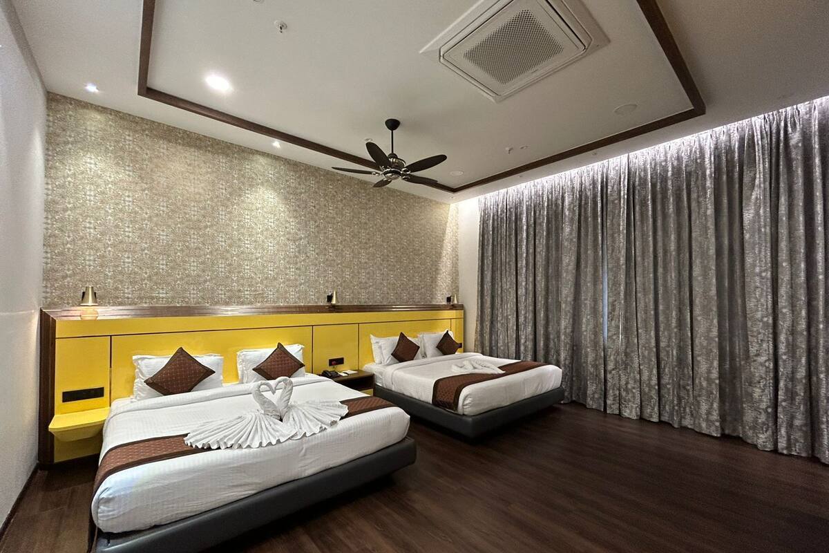 Ein Hotelzimmer mit zwei Betten, einem Deckenventilator und einem großen Fenster mit Vorhängen.