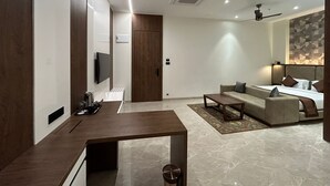 Ein modernes Hotelzimmer mit einer Couch, einem Bett, einem Couchtisch und einem an der Wand montierten Fernseher.