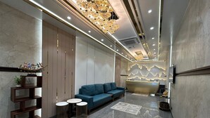 Eine moderne Lobby mit einer Rezeption, einem blauen Sofa und einer Wandverkleidung.