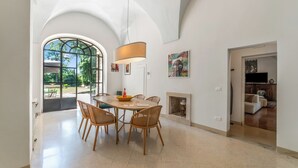 A spacious dining area with a high ceiling, a large window, and a fireplace.