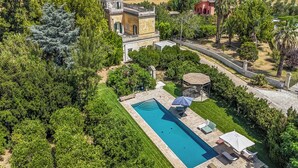 An aerial view of a property with a swimming pool, outdoor seating, and lush greenery.