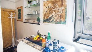 Una cucina con tavolo da pranzo apparecchiato per la colazione, una finestra con vista e scaffali con stoviglie.