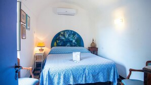 Una camera da letto con un letto, una sedia, un comodino, una lampada e un condizionatore d'aria a parete.