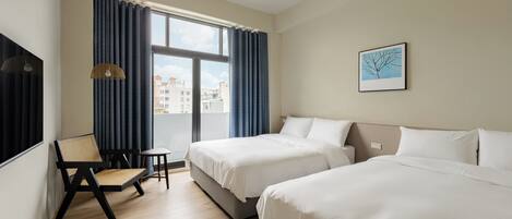 A hotel room with two beds, a chair, a small table, and a window with curtains.