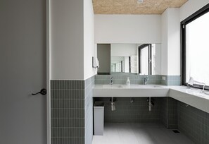 A modern bathroom with a white sink, two faucets, and a mirror above it.