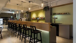 Un espace bar avec un comptoir, des tabourets et une étagère remplie de bouteilles.