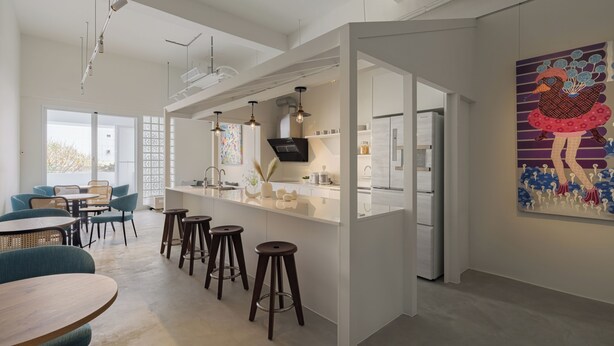 Une cuisine moderne dotée d’un îlot central, de tabourets de bar et d’un coin repas avec des chaises.