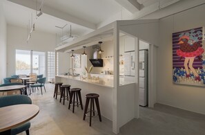 A modern kitchen with a central island, bar stools, and a dining area with chairs. - Timios Inn. (Changhua)