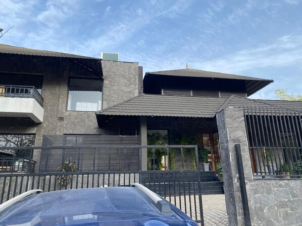 A modern two-story house with a garage, a balcony, and a gated entrance.