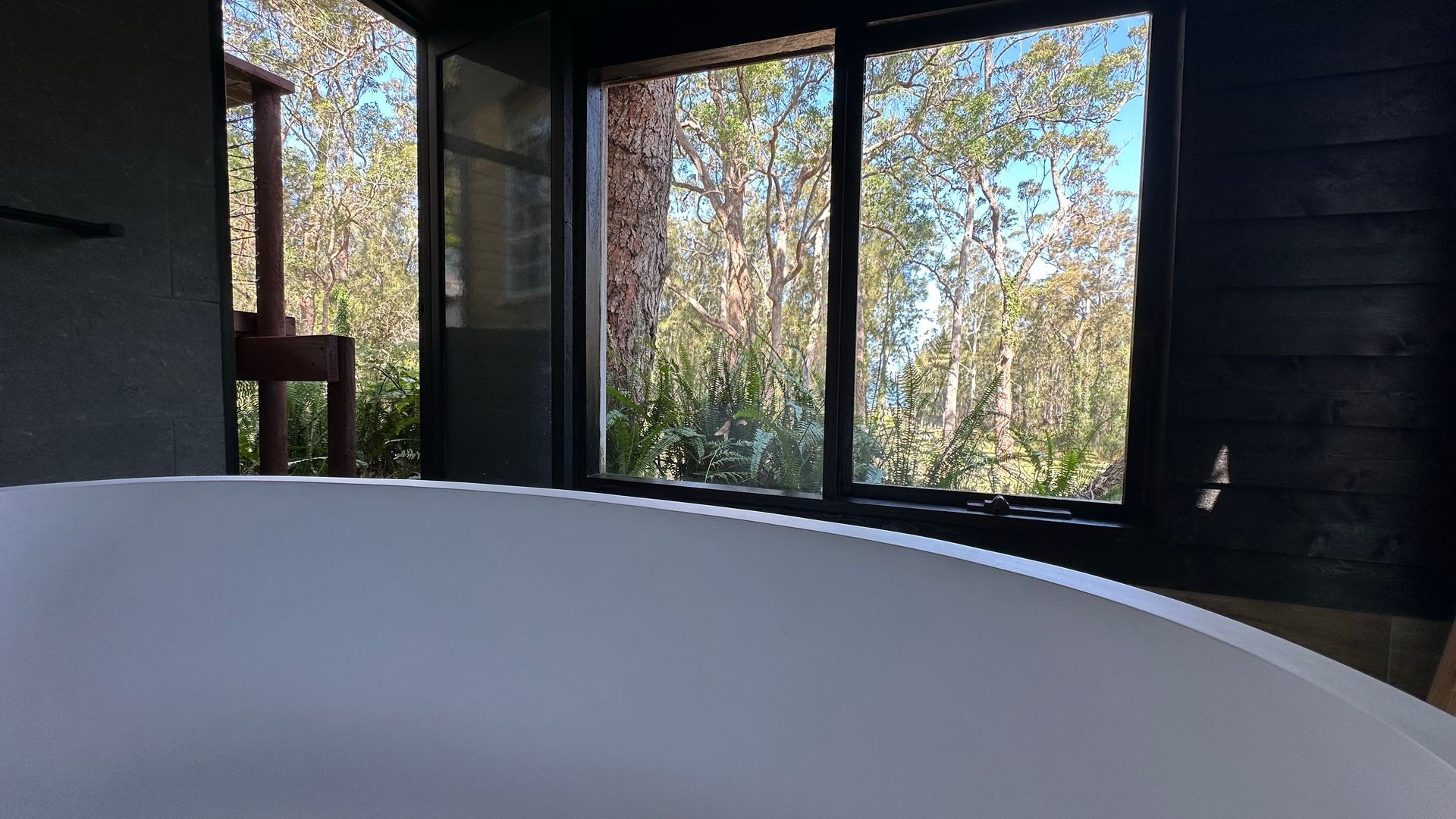 Una habitación con un ventanal grande, una bañera blanca y una silla de madera.