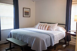 A neatly made bed with pillows, a bedside table with a lamp, and a bench. - The Blue Jay House in North Fondren (Jackson)