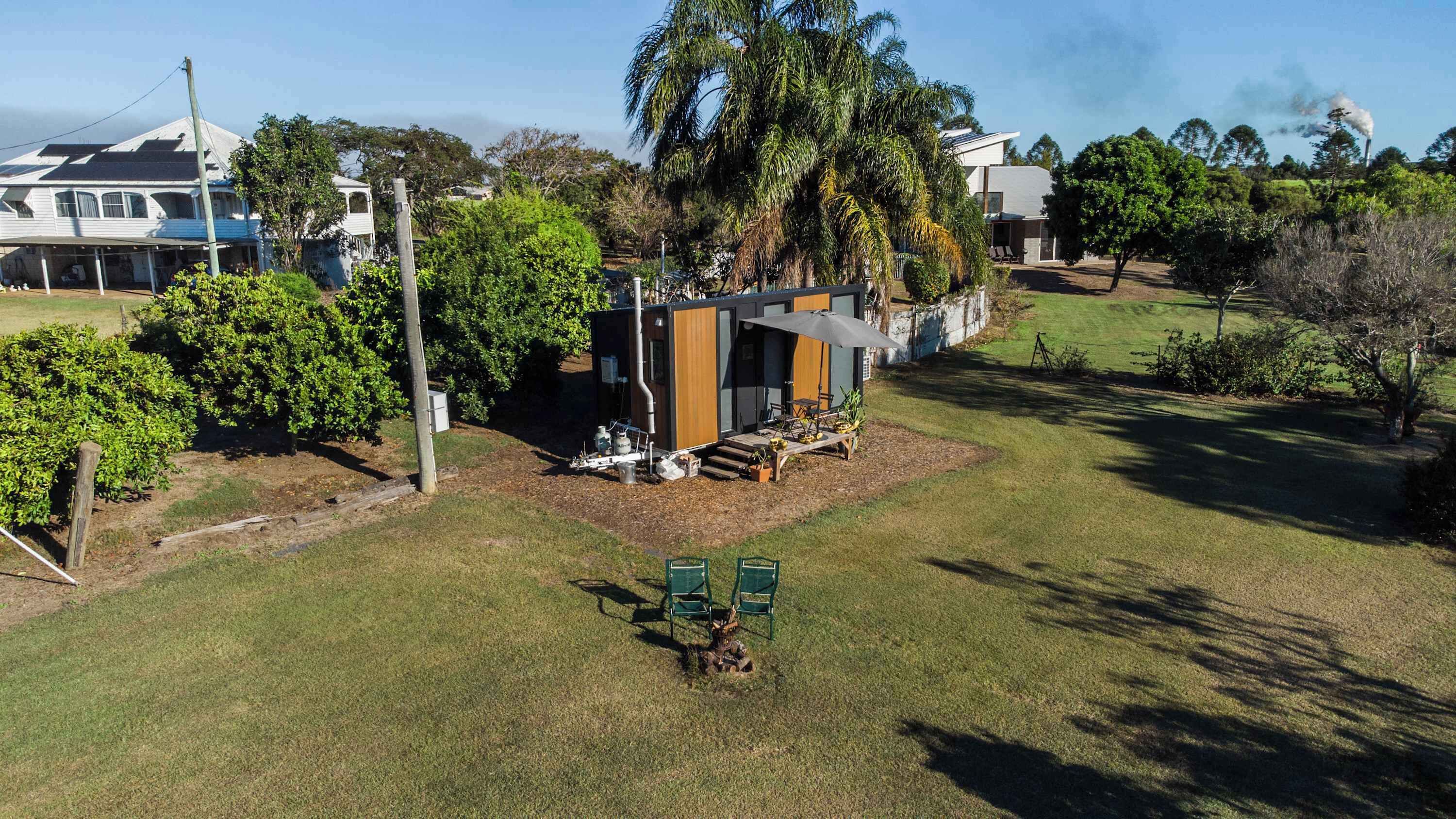 Een modern huis met een terras, omgeven door weelderige begroeiing en een heldere lucht.