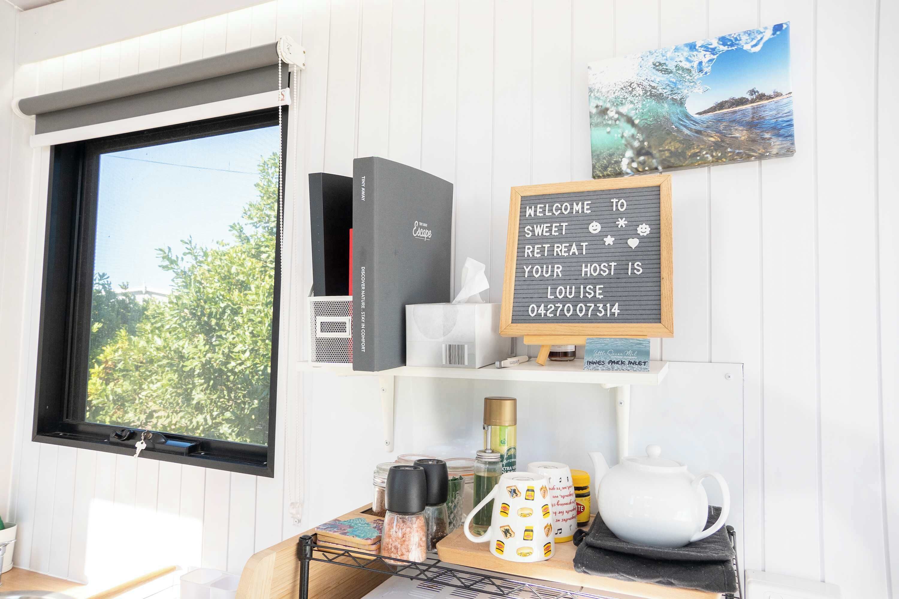 A room with a window, a welcome sign, a coffee station, and a view of the outdoors.