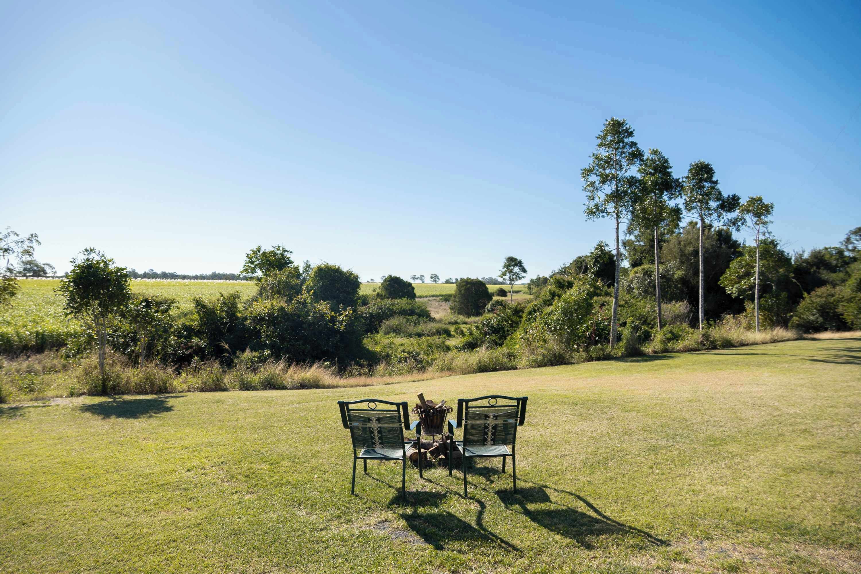 A grassy field with two metal chairs and a table.