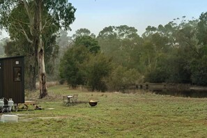 A rustic cabin with a small outdoor seating area and a fire pit. - Cathedral Views by Tiny Away (Buxton)