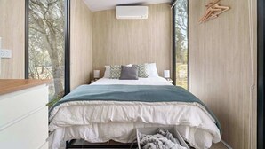 A bedroom with a large bed, a window, and a wooden wall.