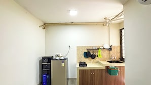 Eine kompakte Küche mit Kühlschrank, Kaffeemaschine, Spüle und einer gefliesten Spritzschutzwand.