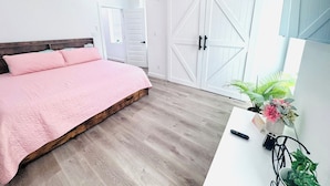 A bedroom with a bed, a wardrobe, a desk, and a potted plant. - 4bed/3bath House in St. Louis (St. Louis)