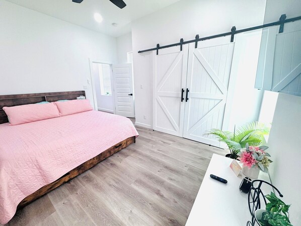 Une chambre à coucher avec un lit, une armoire, un bureau et une plante en pot.