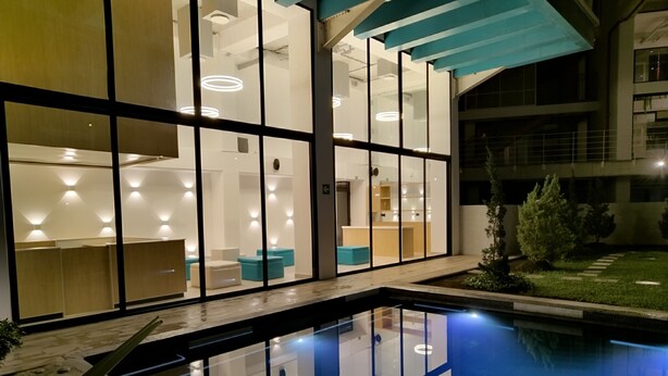 A modern hotel interior with a glass pool, reflecting the interior lights. - Apartamento Moderno en Ciudad Cayalá (Ciudad de Guatemala)