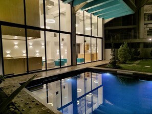 A modern hotel interior with a glass pool, reflecting the interior lights.
