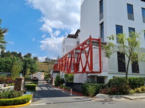 A modern building with a red truss structure, a gated entrance, and well-maintained landscaping.