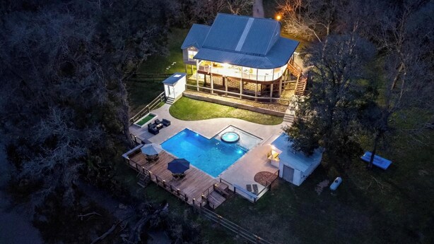 Una casa grande con piscina, terraza y mobiliario exterior.