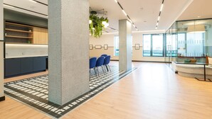 Un interno moderno con una reception, una zona salotto e ampie finestre.