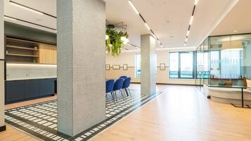 A modern interior with a reception desk, seating area, and large windows.