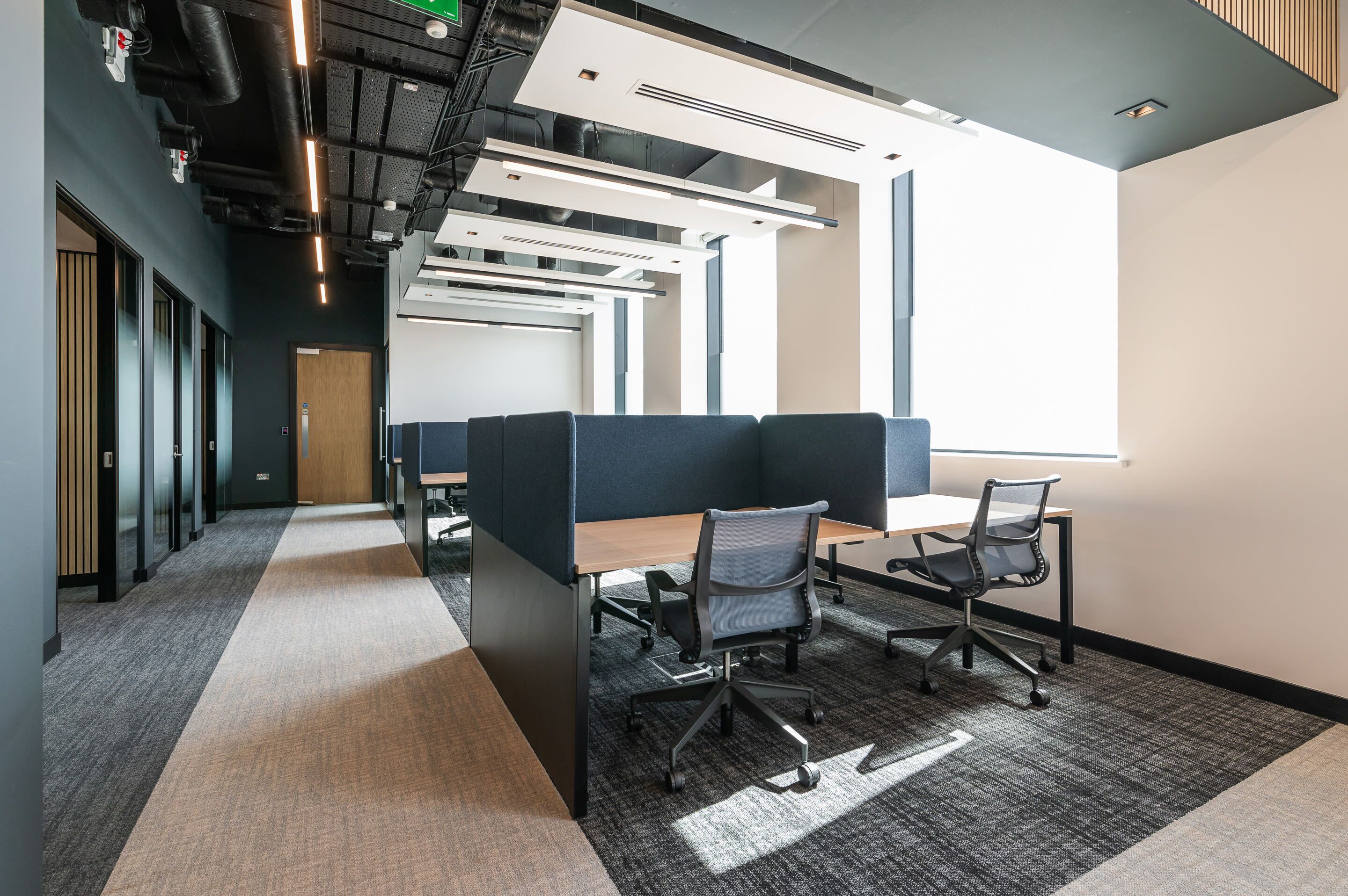 A modern office space with cubicles, desks, and chairs.