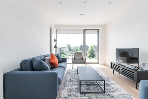 A modern living room with a sofa, armchair, coffee table, and TV.