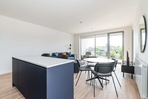 Eine moderne Wohnung mit Kücheninsel, Essbereich und Balkon mit Blick auf die Stadt.