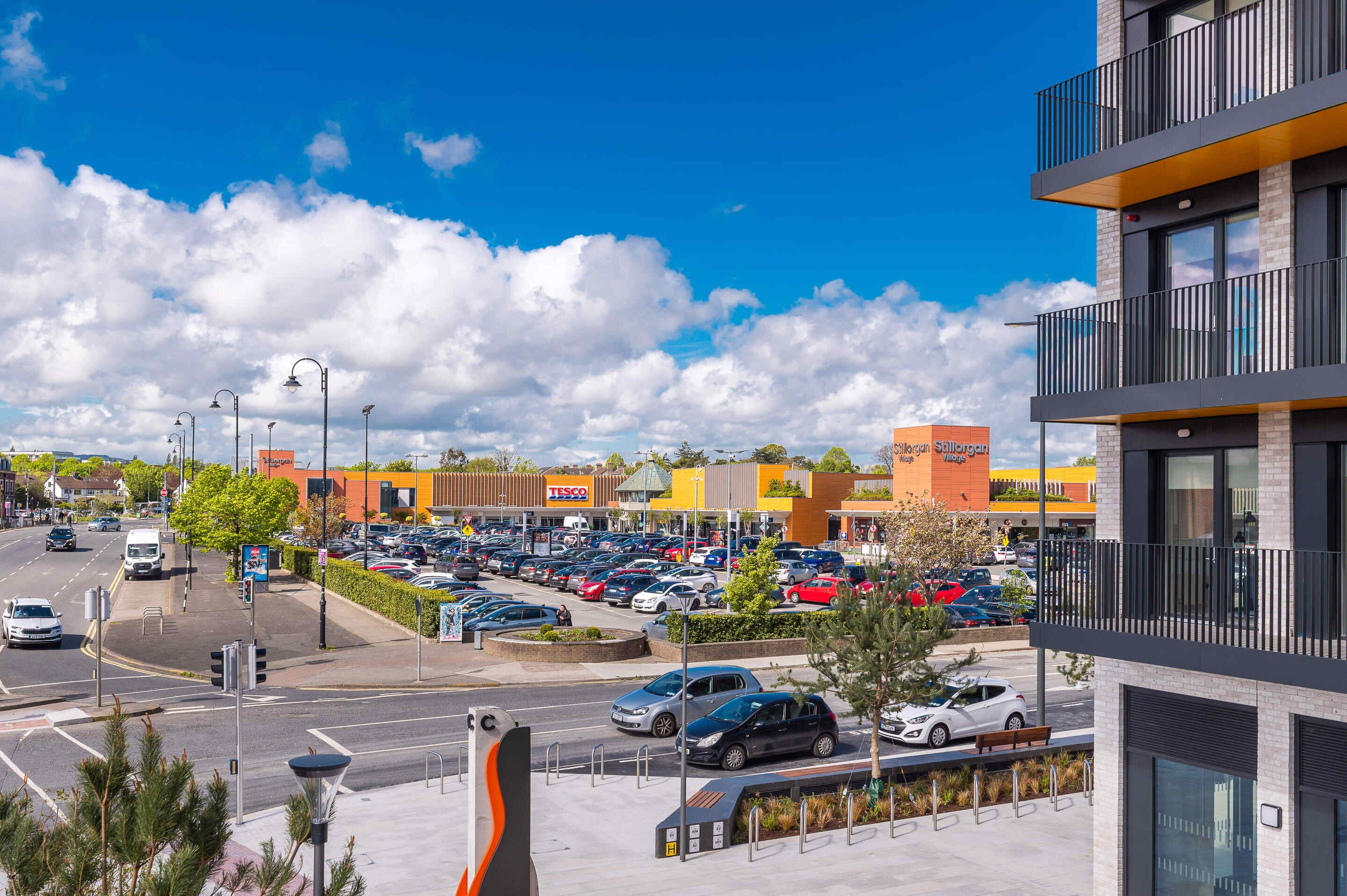A parking lot with multiple cars, a road intersection, and a building with a sign that reads 'TESCO'.