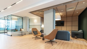 Un intérieur moderne avec un coin salon, une cloison en verre et un téléviseur fixé au mur.