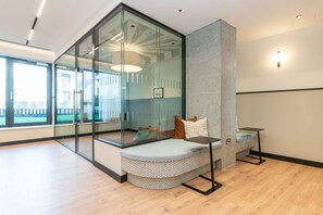 A modern room with a glass partition, a cushioned bench, a small table, and a patterned wall. - The Cornerstone Two by Dublin At Home (Dublin)