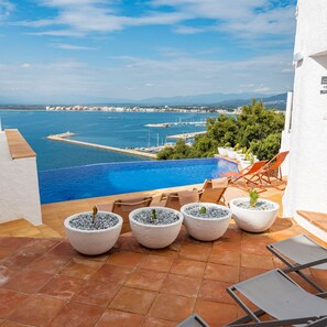 A poolside area with a view of the sea, outdoor seating, and potted plants. - Castell Mar 1007 in Roses (Roses)