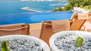 An infinity pool with a view of the sea and a distant cityscape. - Castell Mar 1007 in Roses (Roses)