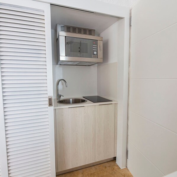 A compact kitchenette with a built-in microwave, a sink, and a small countertop.