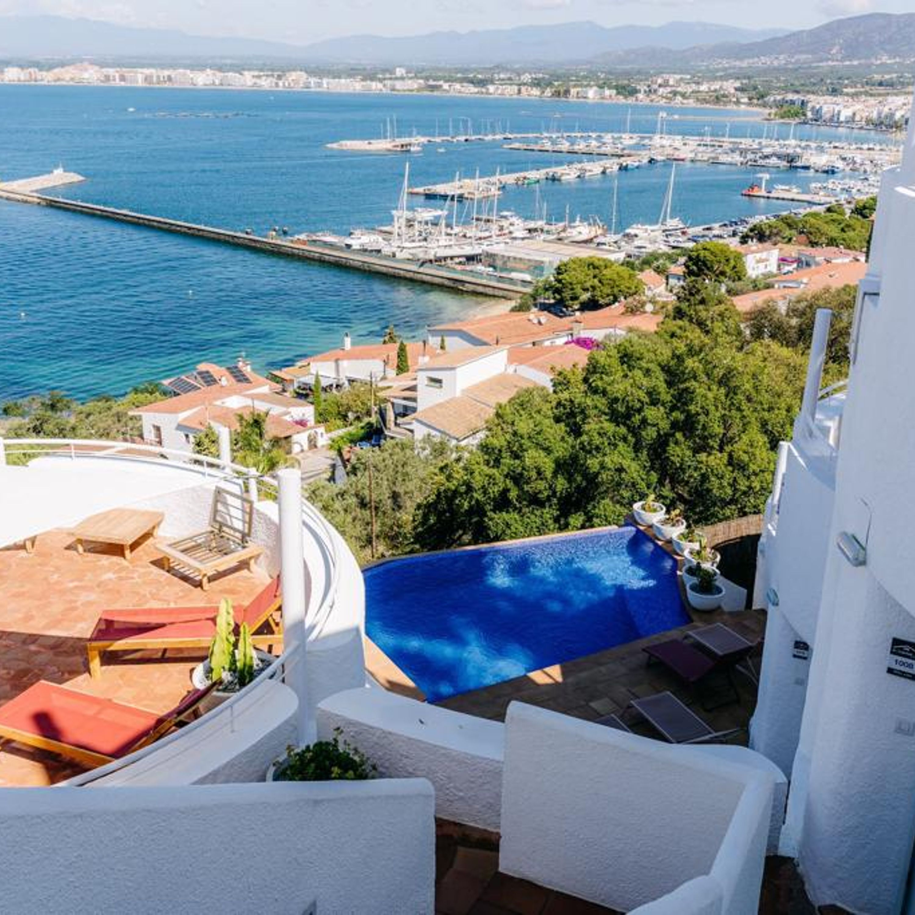 A rooftop pool with a view of a marina and cityscape.