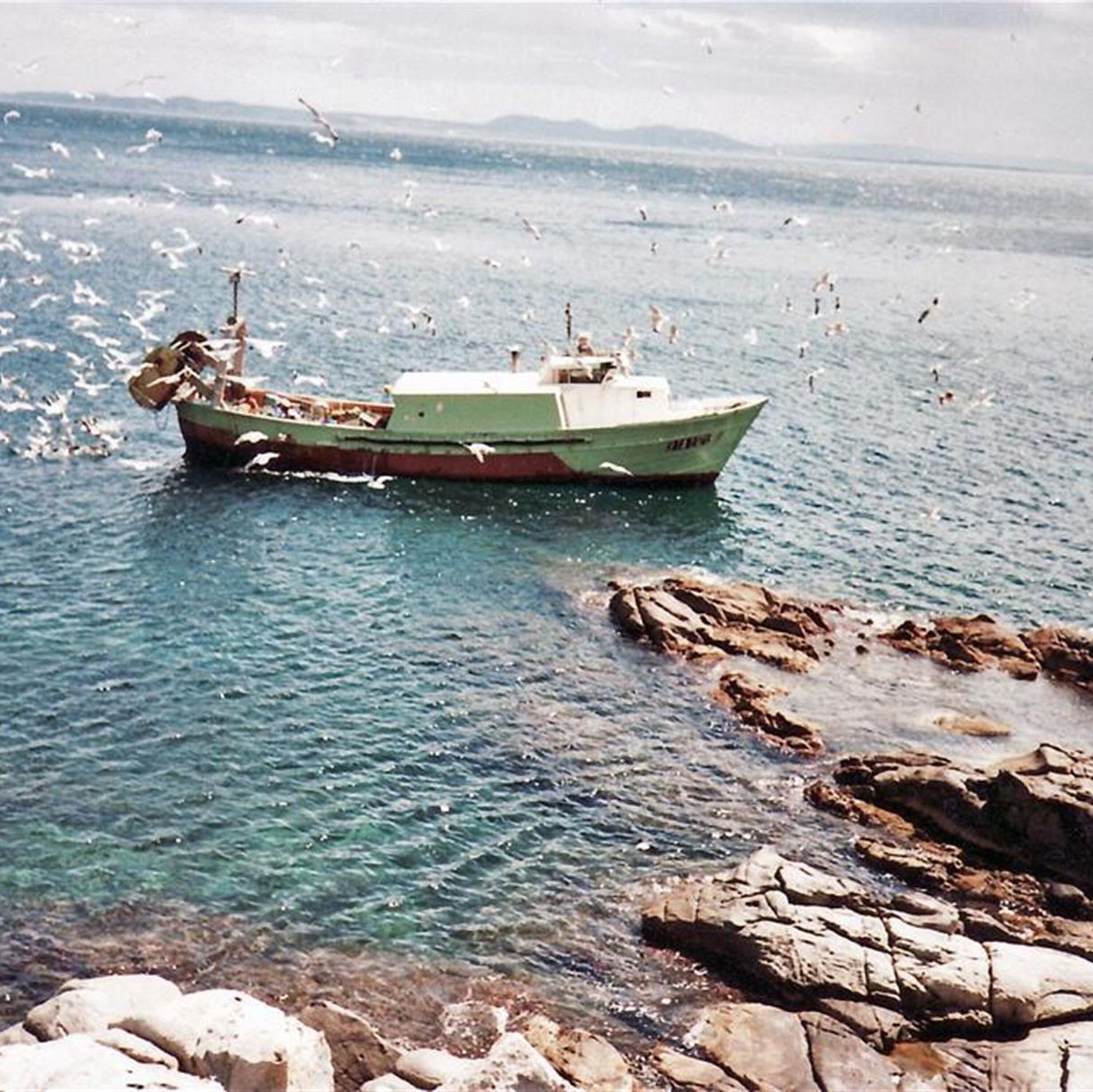 A boat on calm water near rocky shores.